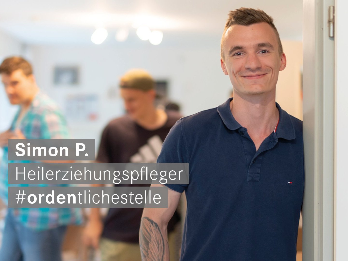 Heilerziehungspfleger mit Tattoos laechelt freundlich in die Kamera