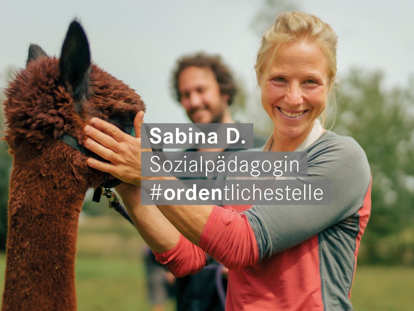 Sozialpaedagogin mit blonden Haaren und Alpaka laechelt freundlich in die Kamera